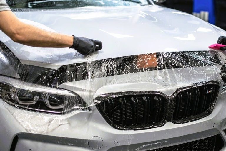 Två personer som applicerar PPF på en silvrig BMW
